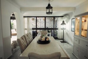 Un espace repas avec une longue table, un banc rembourré et des fleurs décoratives.