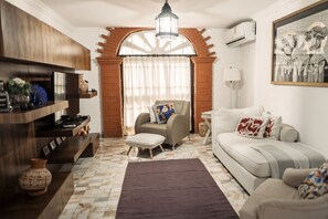 Un salon comprenant un canapé, une table basse, une cheminée et une grande fenêtre avec des rideaux.