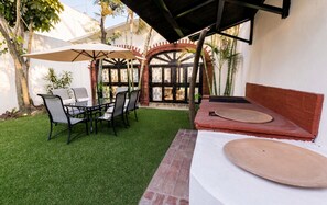 Un espace patio avec une table et des chaises, un coin salon abrité et un mur décoratif.