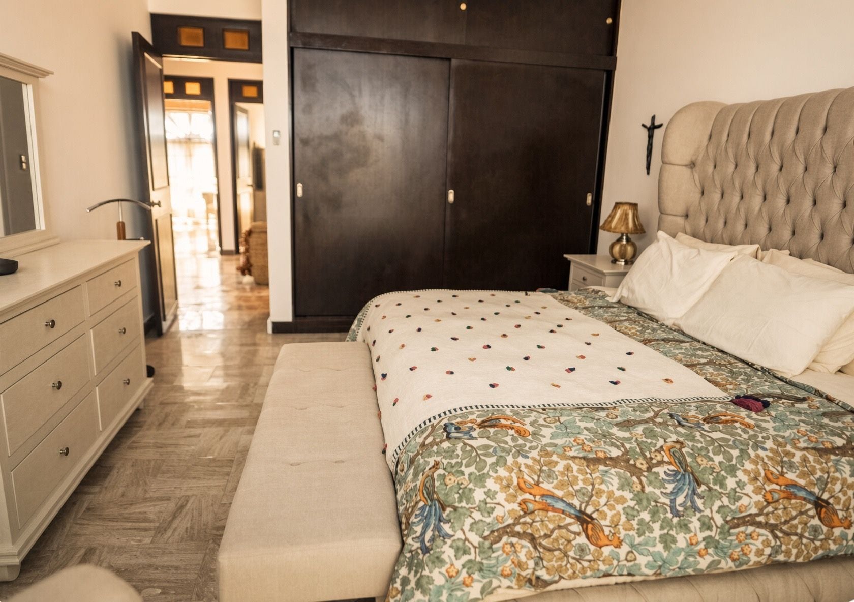Een slaapkamer met een bed, een bankje, een dressoir, een garderobe en een nachtkastje.