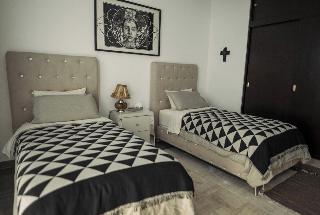 Un dormitorio con dos camas, una mesita de noche, una lámpara y un cuadro en la pared.