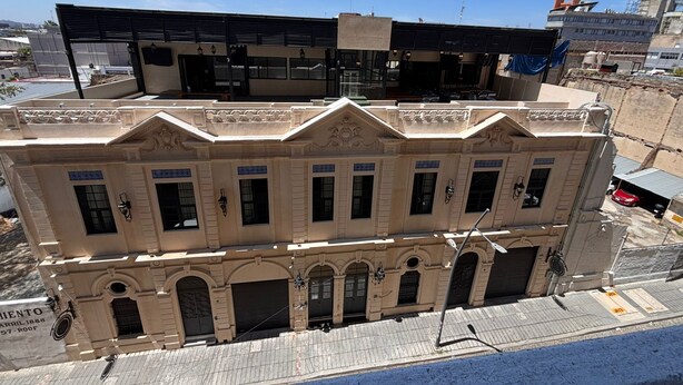 Un edificio de varios pisos con fachada clásica, que presenta ventanas arqueadas y molduras decorativas.