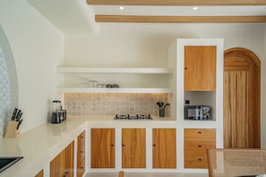 A modern kitchen with white cabinetry, a gas stove, and a wooden archway. - Palmera Moana Uluwatu (Pecatu)