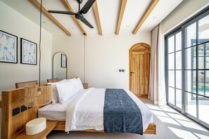 A modern bedroom with a large bed, wooden headboard, and a ceiling fan. - Palmera Moana Uluwatu (Pecatu)