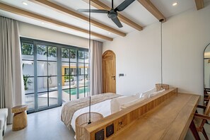 A modern bedroom with a large bed, a ceiling fan, and a view of an outdoor pool area. - Palmera Moana Uluwatu (Pecatu)