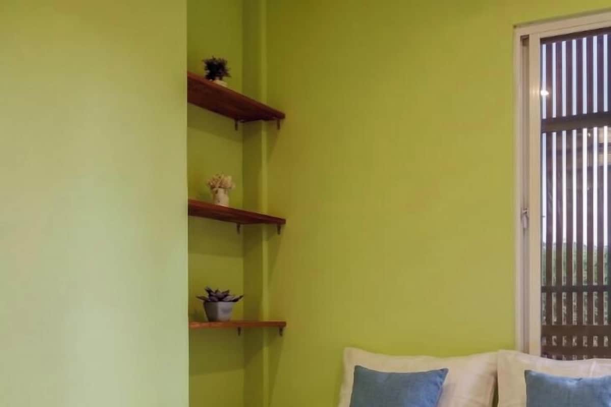Una habitación con una cama, una ventana con persianas y un estante con adornos.