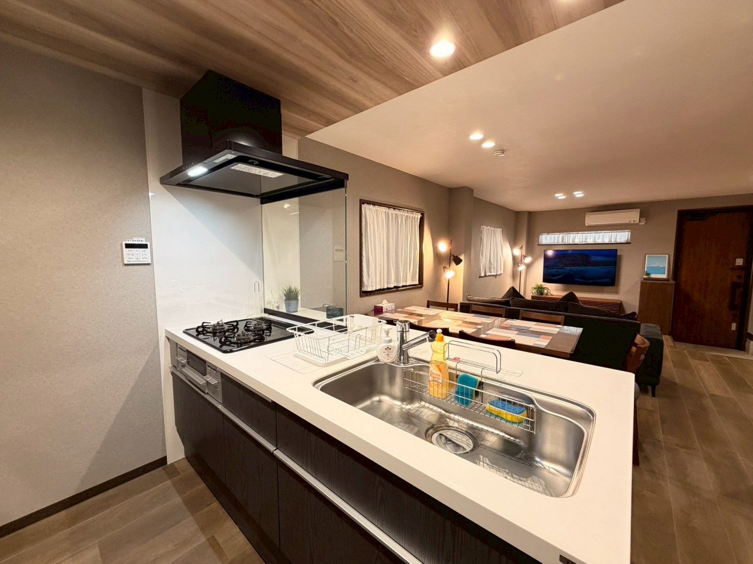 A modern kitchen with a central island, built-in appliances, and a dining area with a flat-screen TV.