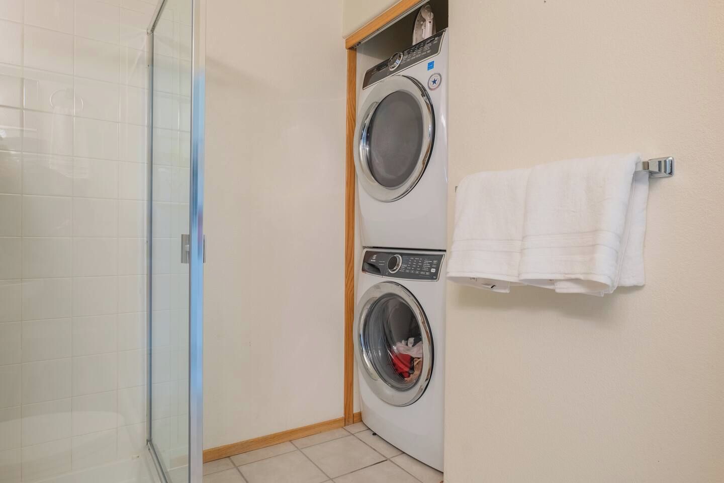 A laundry room with two washing machines and a glass shower enclosure.
