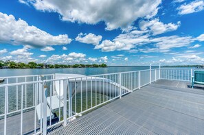 Eine Steg mit Metallgeländer, eine Treppe, die zum Wasser führt, und Blick auf einen See mit einer fernen Uferlinie.