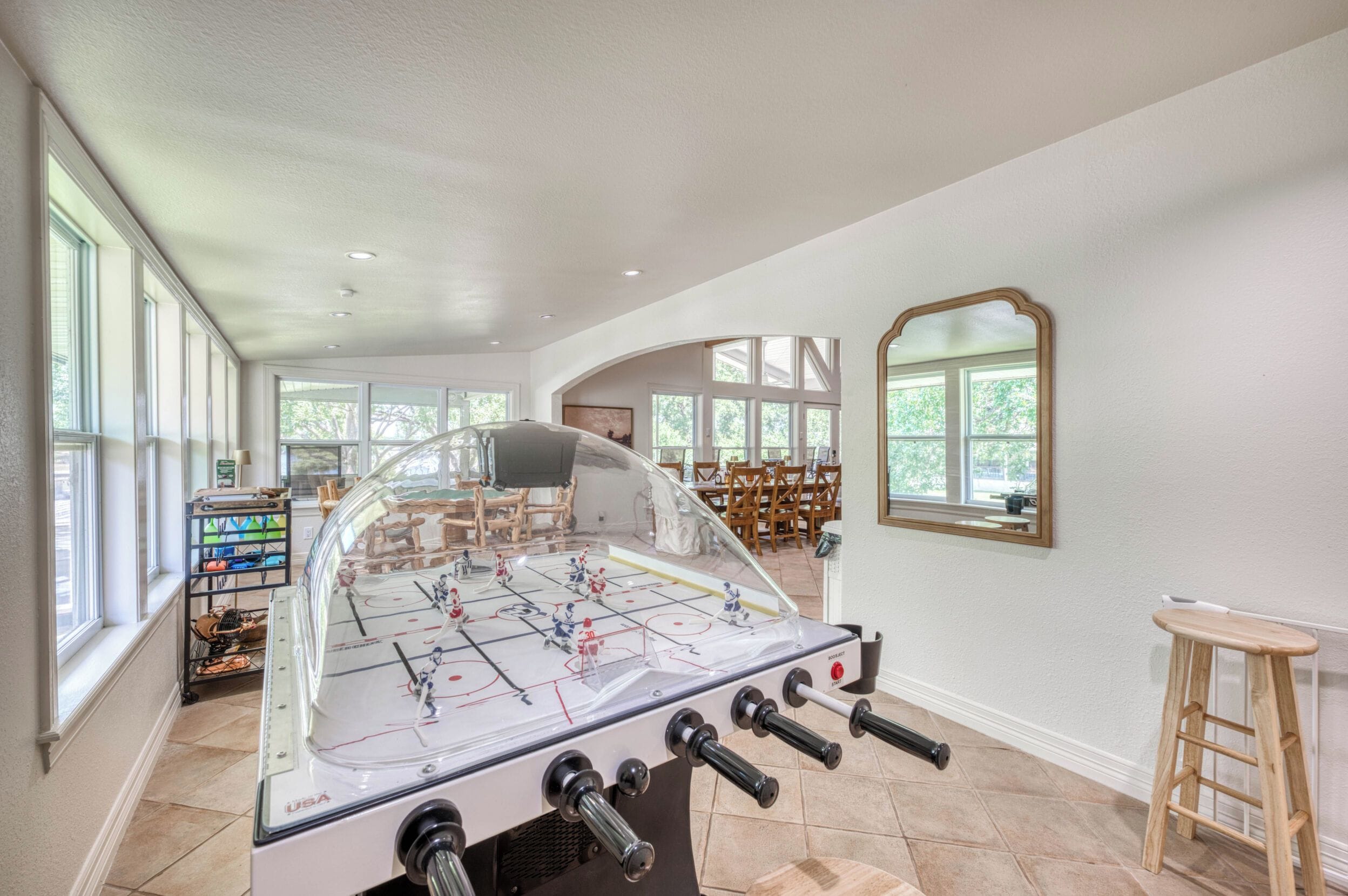 A room with a foosball table, a wooden chair, and a ladder.