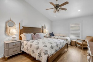Ein Schlafzimmer mit einem hölzernen Bett, Nachttischlampen, einem Deckenventilator und einem Fenster mit Jalousien.
