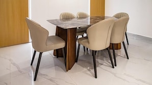 Een eetruimte met een marmeren tafel en zes stoelen.