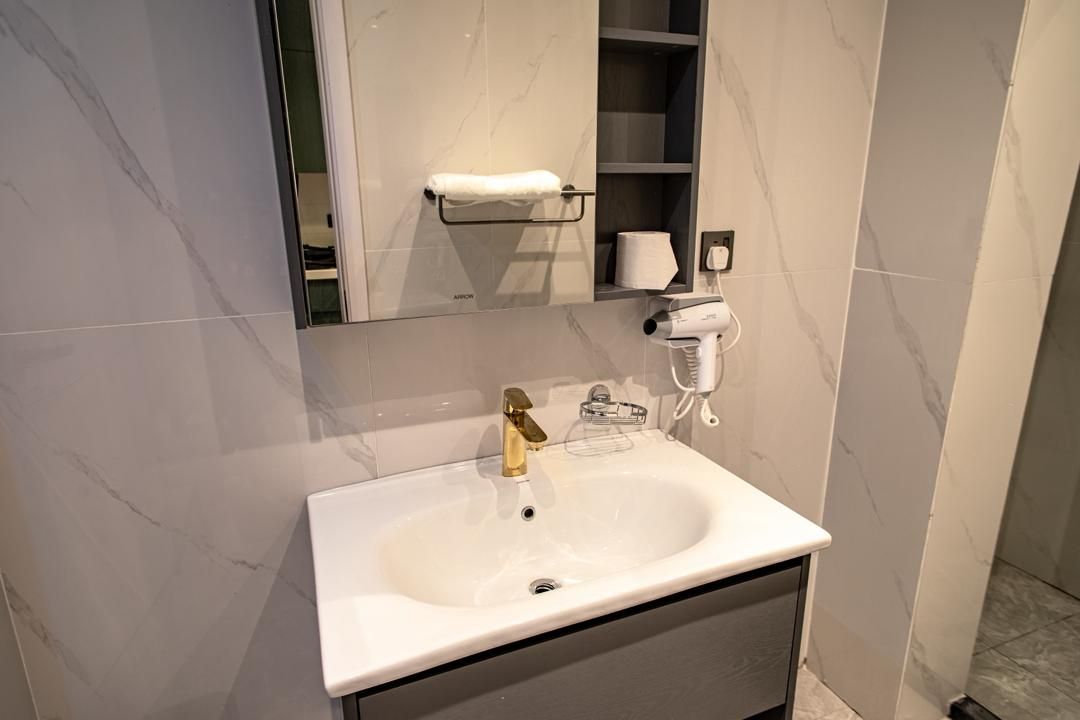 A bathroom with a white sink, a towel rack, a mirror, and a hairdryer on the wall.
