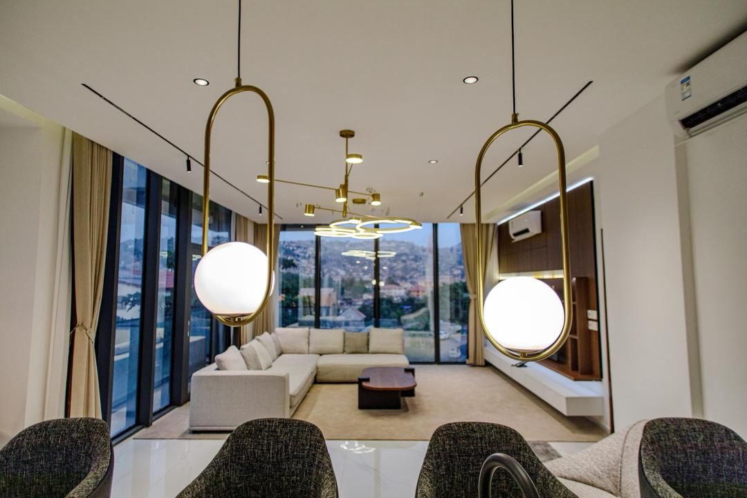 Una habitación de hotel moderna con un ventanal grande, un sofá, una mesita de centro y un rincón de estar con sillones.