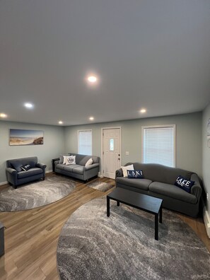 A living room with three sofas, a coffee table, and a painting on the wall.