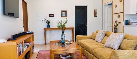 A living room with a sofa, coffee table, bookshelf, and a television.