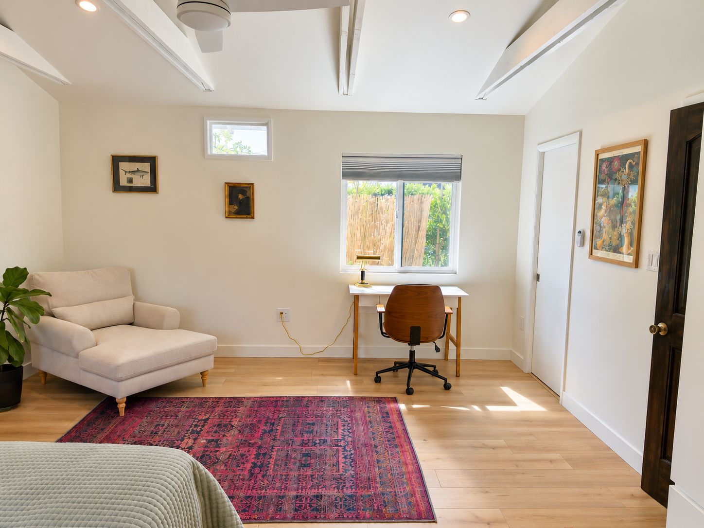 A room with a desk, chair, and a large window.