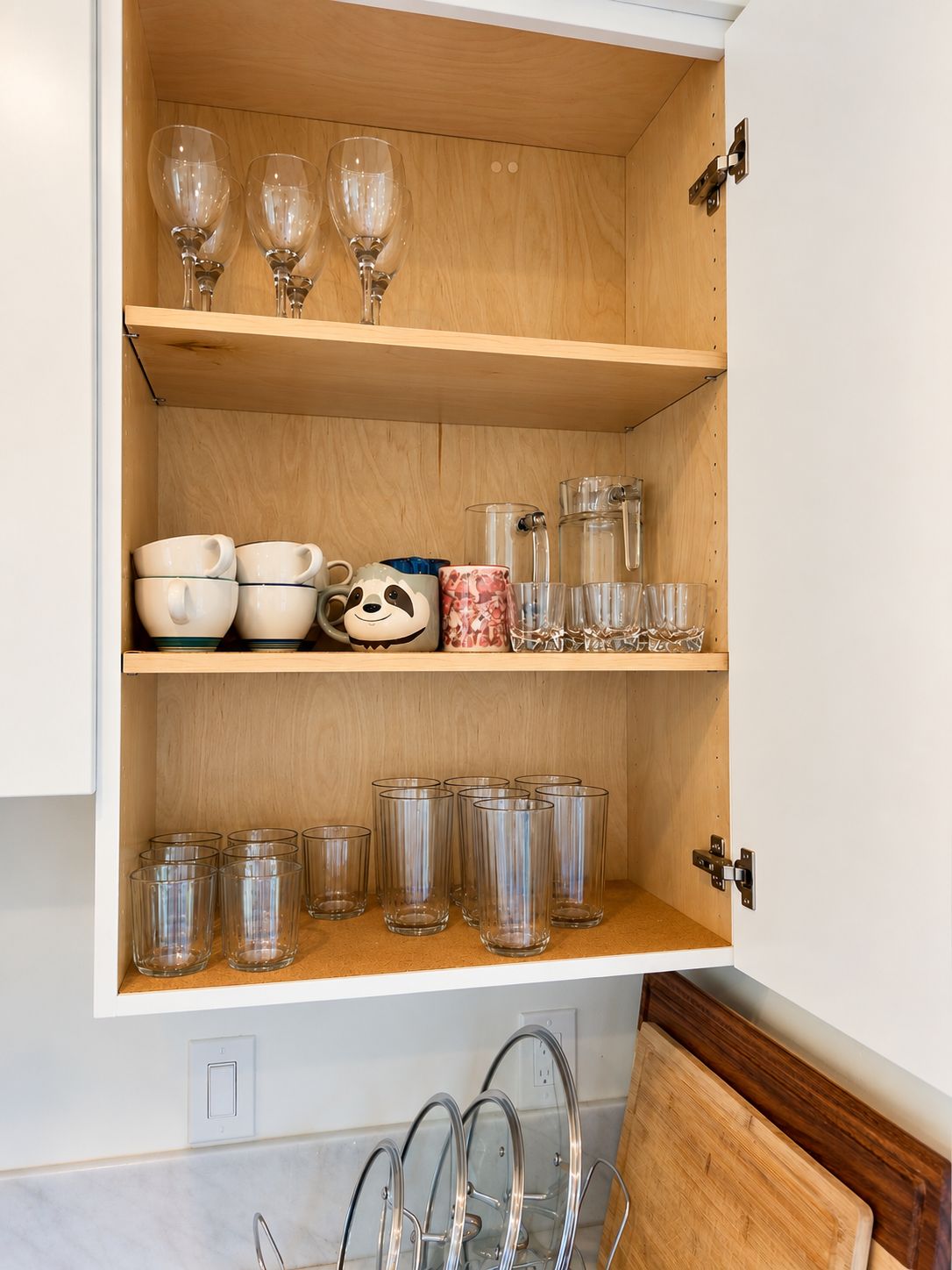 Un armario de cocina con estantes que contienen diferentes vasos y tazas.