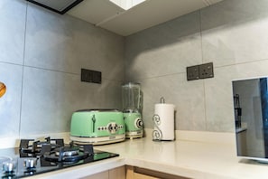 A kitchen with a gas stove, two vintage appliances, a blender, and a paper towel holder. - 3-bedroom apartment in Westlands perfect Family friendly retreat, Pool, Gym, Wow (Nairobi)