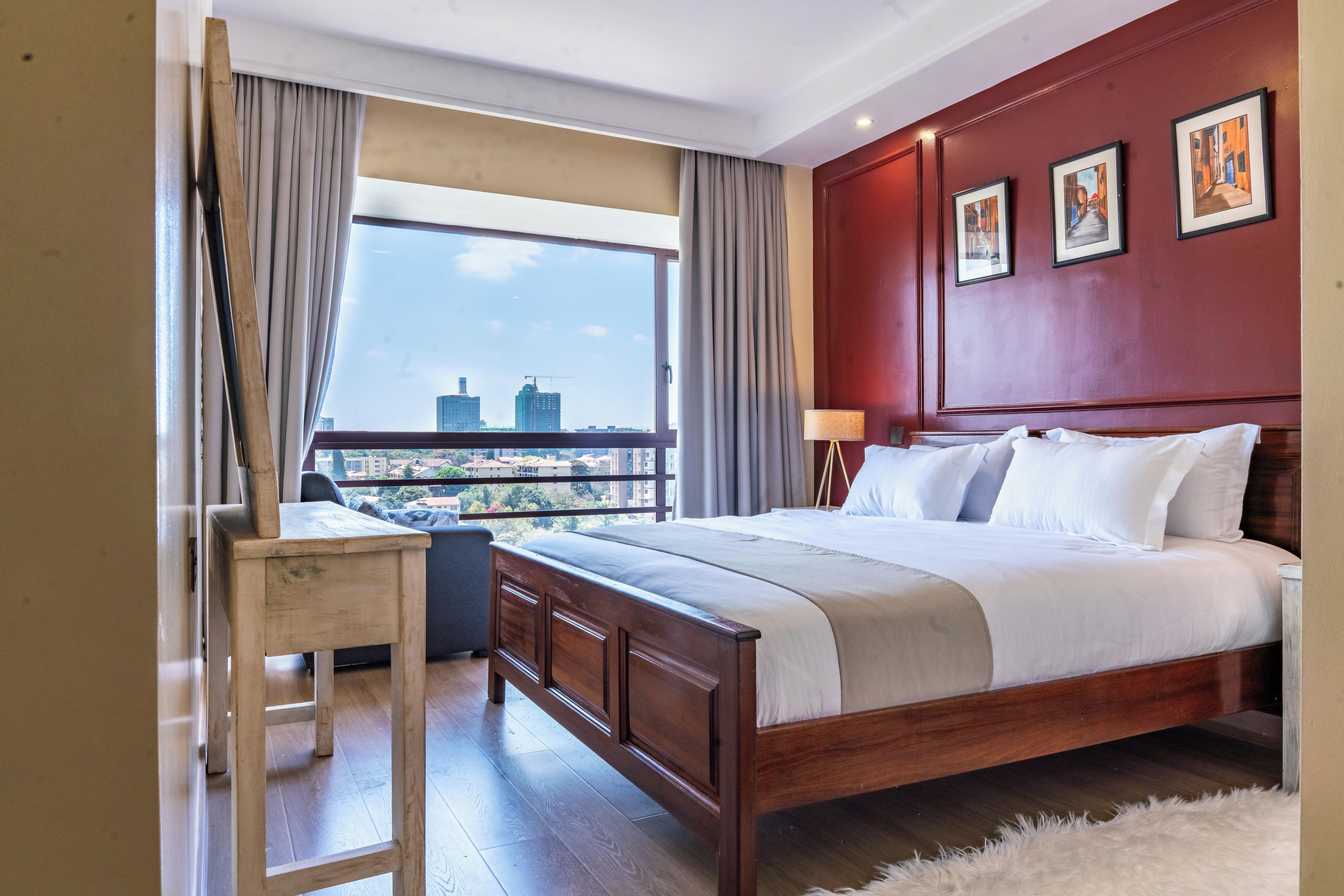 A hotel room with a large bed, a desk, and a view of the cityscape.
