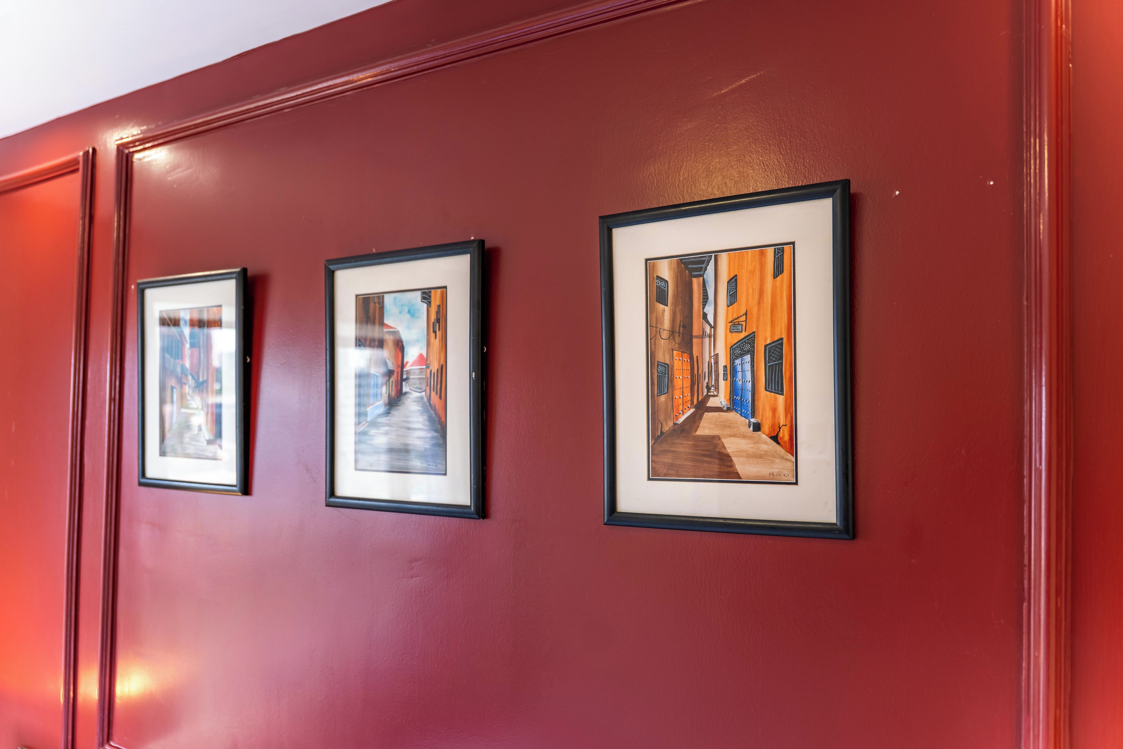 Een gang met drie kunstwerken in lijsten aan de muur.