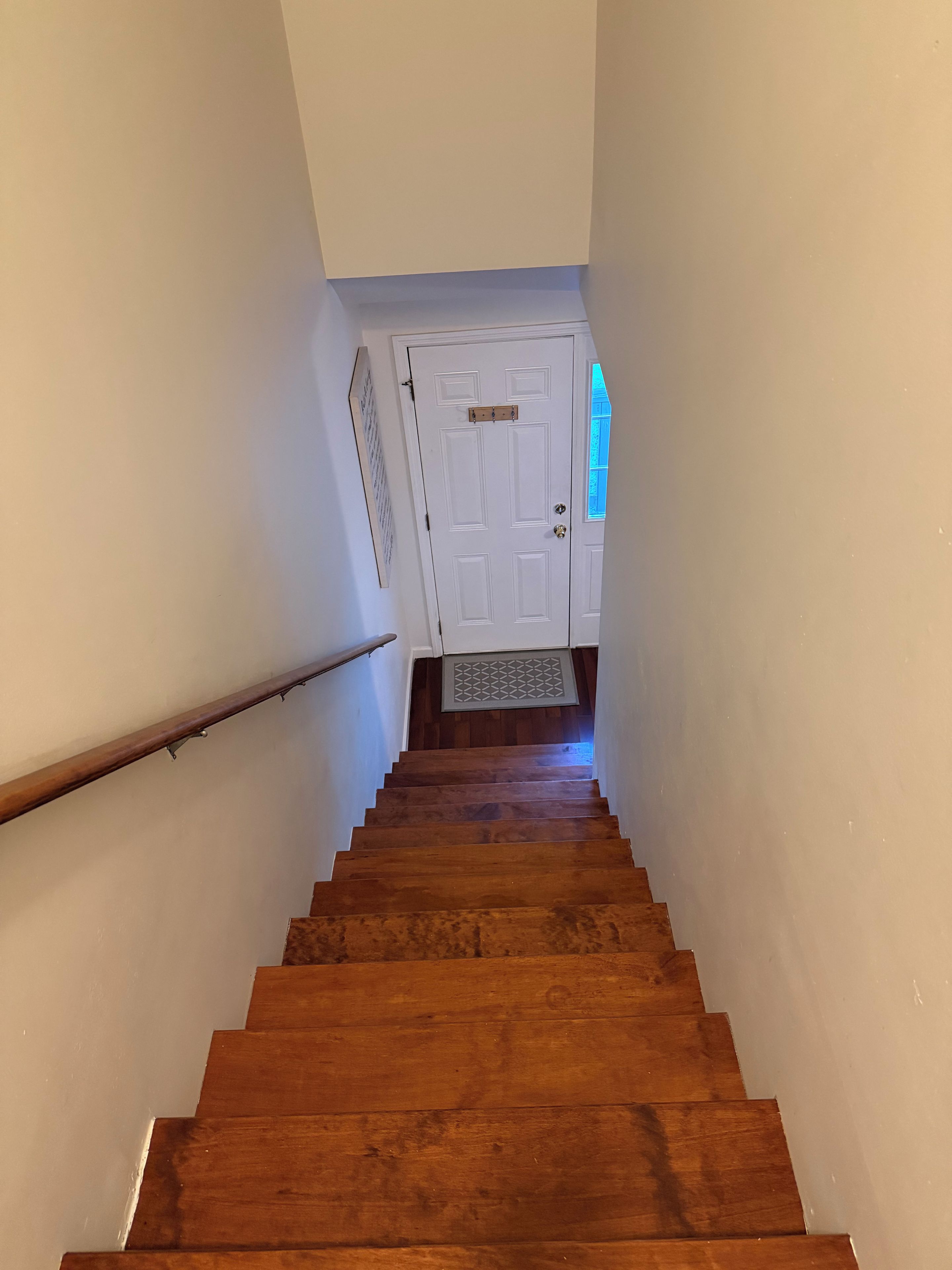 A wooden staircase leading to a white door with a small window.