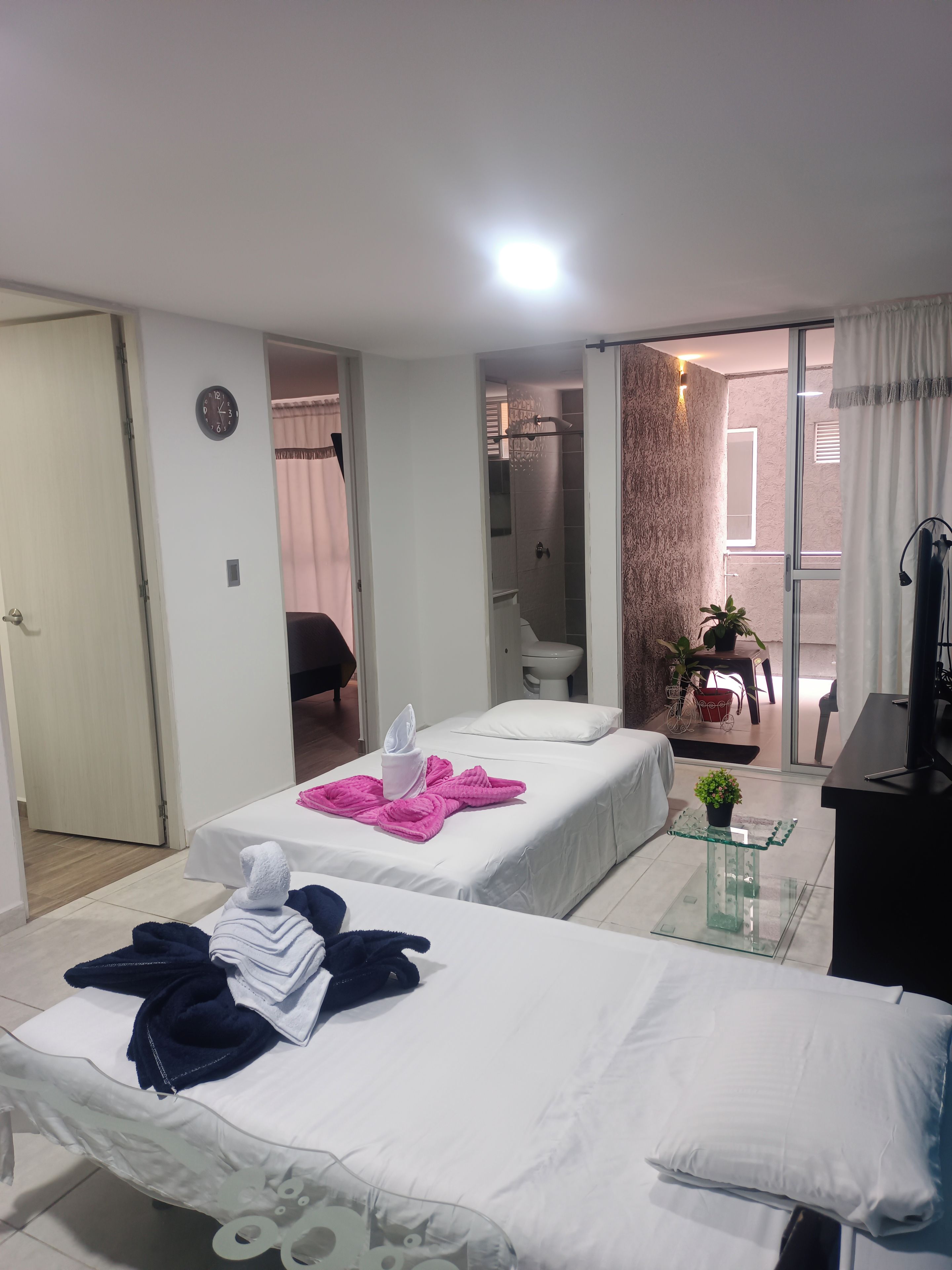 A hotel room with two beds, a bathroom, and a balcony.