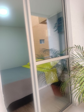 Ein Zimmer mit Bett, Fenster und einer Topfpflanze.