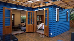 A blue cabin with a wooden deck, a sofa, a table, and a bed. - Kingsleigh Daylesford (Daylesford)