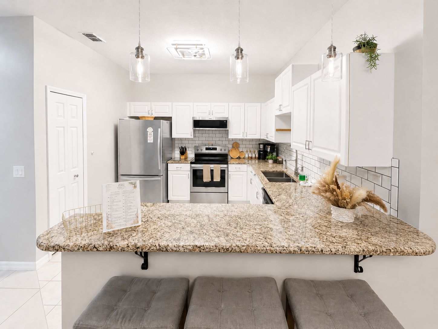 A modern kitchen with white cabinets, a granite countertop, and a built-in bench.