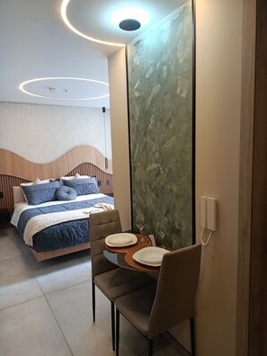 A modern hotel room with a bed, a dining area with a table set for two, and a large mirror. - Luxurious studio apartment in Quito's financial district (Quito)
