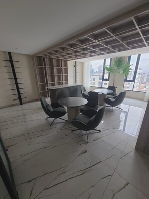 A modern interior with a round table and chairs, a bookshelf, and a city view through large windows. - Luxurious studio apartment in Quito's financial district (Quito)