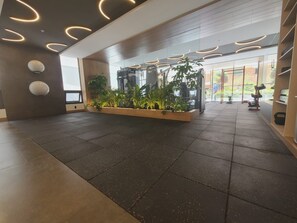 A spacious lobby with a modern design, featuring a large planter with various plants, a reception desk, and a visible gym area in the background. - Luxurious studio apartment in Quito's financial district (Quito)