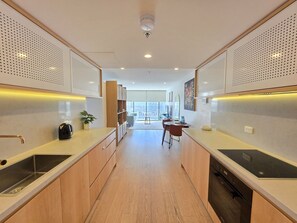 A modern kitchen with a central island, wooden cabinets, and a view to the outside. - High-End 1BR with Enclosed Balcony Near ANU (Braddon)