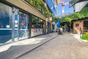 A building with large glass windows, a blue awning, and a brick wall. - High-End 1BR with Enclosed Balcony Near ANU (Braddon)