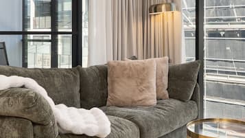 Una sala de estar moderna con un sofá gris, una manta blanca y una mesa de centro redonda de vidrio.