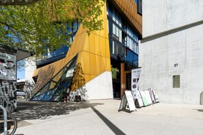 A modern building with a unique angular facade, a concrete wall with a number, and a bicycle parked outside. - High-End 1BR with Enclosed Balcony Near ANU (Braddon)