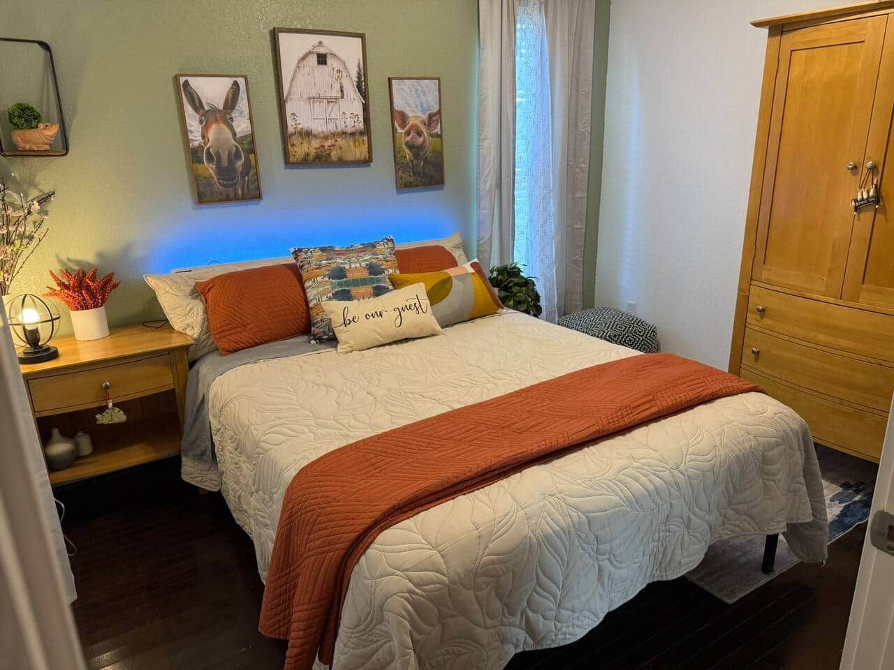 A bedroom with a bed, a nightstand, a dresser, and wall art.