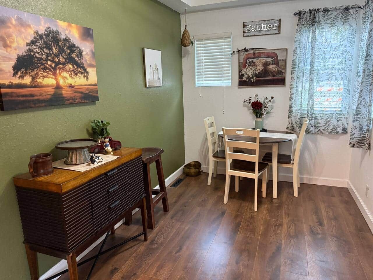 Un comedor con una mesa y sillas de madera, una radio antigua y un cuadro de un árbol.