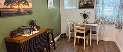 Un comedor con una mesa y sillas de madera, una radio antigua y un cuadro de un árbol.