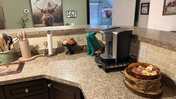 Eine Küche mit Granit Arbeitsplatten, einer Kaffeemaschine und einer Wand mit einer Berg- und Bull-Dekoration.