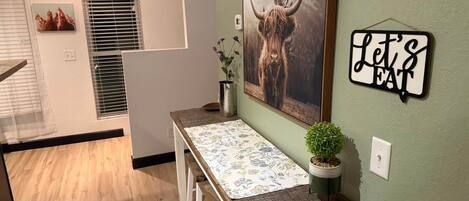 Una cocina moderna con una mesa de madera, una planta en maceta y un letrero en la pared.