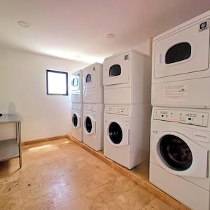 A laundry room with four stacked front-loading washing machines and a single top-loading machine. - Studio Blue Playa del Carmen (Playa del Carmen)