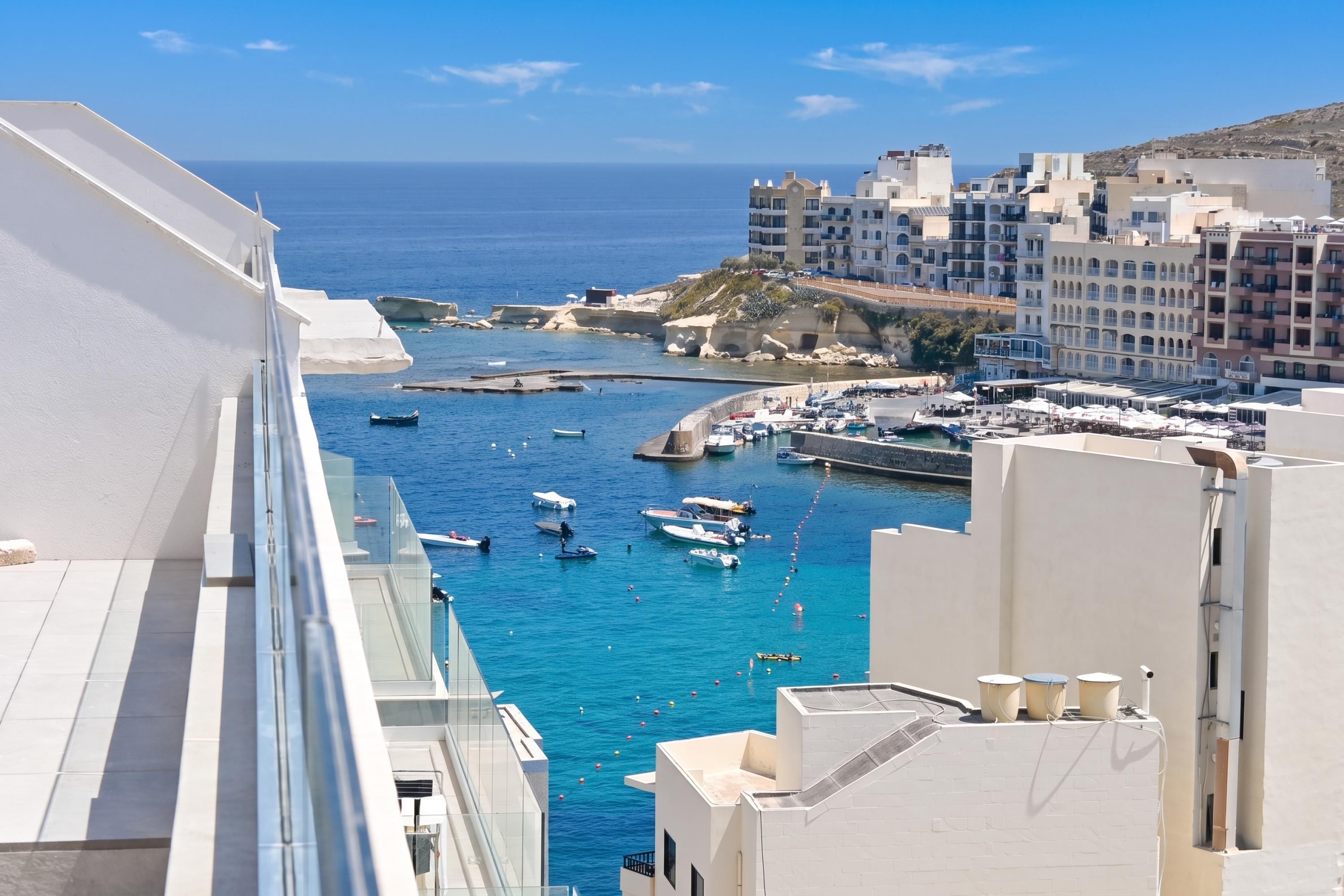 A coastal cityscape with a marina, buildings, and boats.