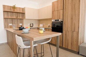 Une cuisine moderne avec des meubles en bois, un four encastré et un coin repas comprenant une table et deux chaises.