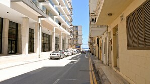 A street with modern buildings, parked cars, and a clear sky. - Penthouse, Jacuzzi & Sea-View in Gozo 7A, Marsalforn Iz-Zebbug Gozo, Malta (Marsalforn Iz-Zebbug Gozo)