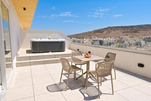 A balcony with a table and chairs, a hot tub, and a city view. - Penthouse, Jacuzzi & Sea-View in Gozo 7A, Marsalforn Iz-Zebbug Gozo, Malta (Marsalforn Iz-Zebbug Gozo)