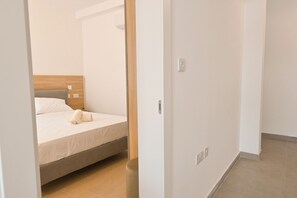 Ein Hotelzimmer mit einem Bett, einem Holz-Kopfteil, einem Nachttisch und einem an der Wand montierten Lichtschalter.