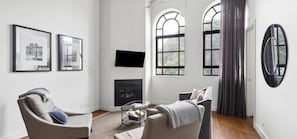 A modern living room with a fireplace, two armchairs, a sofa, and a television mounted on the wall. - Devlin 103 - Stylish Geelong Apartment (Greater Geelong)