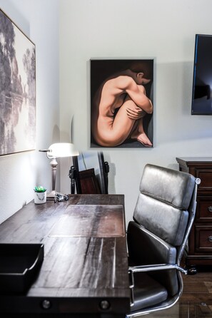 Ein Essbereich mit einem Holztisch, einem schwarzen Ledersessel, einem gerahmten Kunstwerk an der Wand und einer kleinen Topfpflanze.